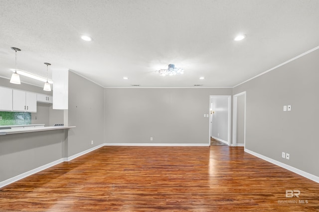 unfurnished living room with baseboards, recessed lighting, wood finished floors, and crown molding