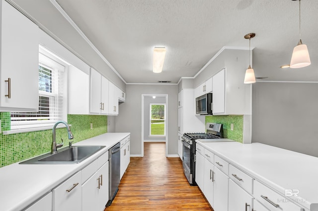 kitchen featuring a wealth of natural light, appliances with stainless steel finishes, white cabinets, backsplash, and a sink