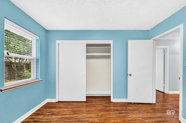 unfurnished bedroom featuring wood finished floors, baseboards, and a closet