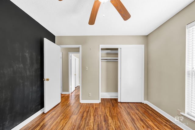 unfurnished bedroom with baseboards, wood finished floors, a ceiling fan, and a closet