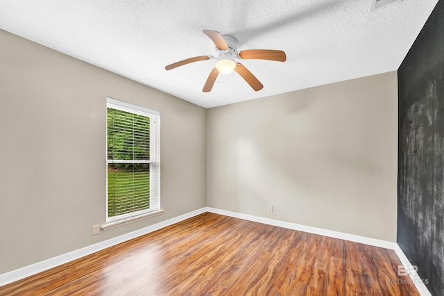spare room featuring a ceiling fan, a textured ceiling, wood finished floors, and baseboards