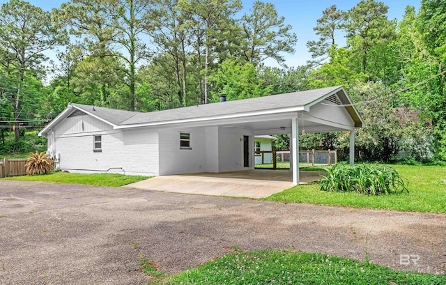 view of front facade featuring brick siding, fence, aphalt driveway, an attached carport, and roof with shingles