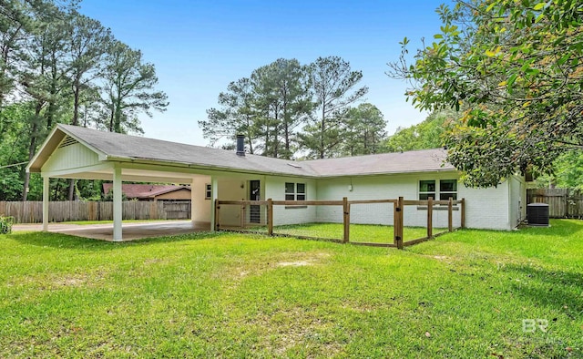 rear view of property with cooling unit, a lawn, a carport, brick siding, and fence