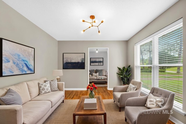 living room featuring baseboards, wood finished floors, an inviting chandelier, and plenty of natural light
