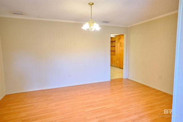 empty room featuring crown molding, a textured ceiling, an inviting chandelier, and light hardwood / wood-style flooring