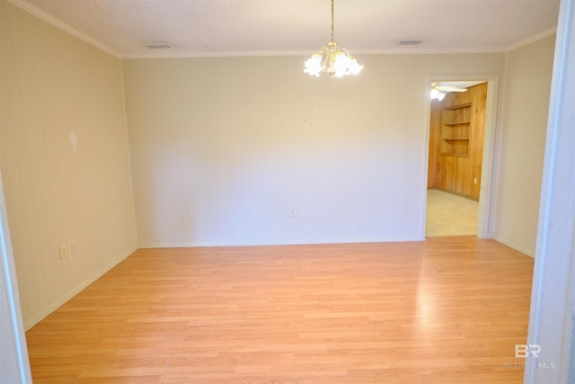 unfurnished room featuring built in shelves, ornamental molding, a chandelier, and light wood-type flooring