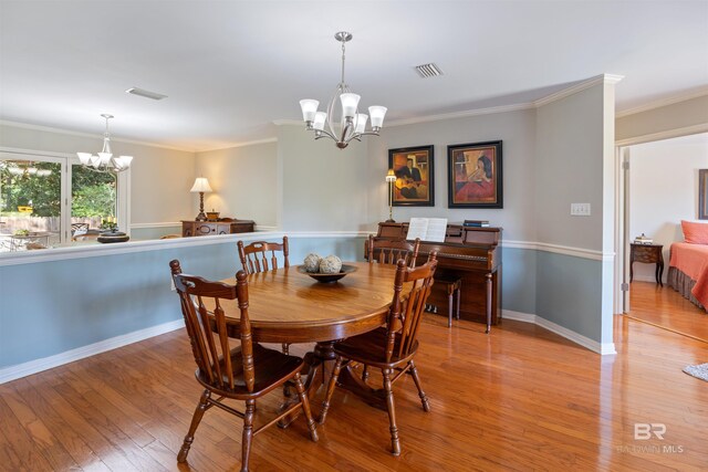 dining area with crown molding, a chandelier, and light wood-type flooring