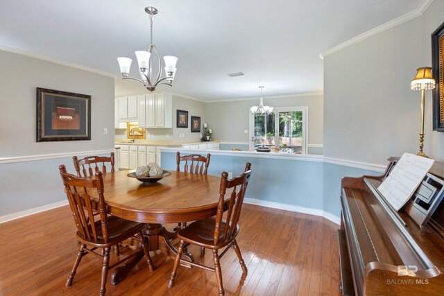 dining room featuring sink, hardwood / wood-style flooring, a chandelier, and crown molding