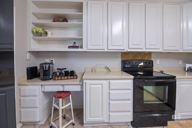 kitchen featuring black electric range oven, white cabinets, and light tile patterned floors