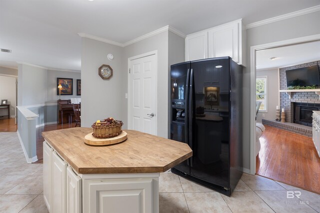 kitchen with a kitchen island, white cabinetry, black fridge, and light tile patterned flooring