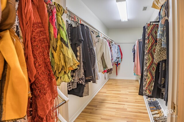 walk in closet with light hardwood / wood-style flooring