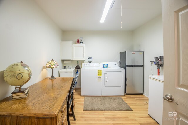 washroom featuring cabinets, light hardwood / wood-style flooring, sink, and washing machine and dryer