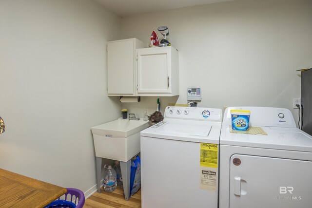 washroom with separate washer and dryer, cabinets, and light wood-type flooring