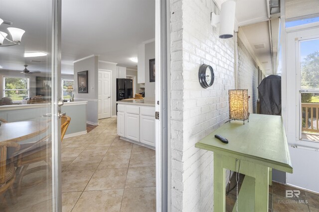 kitchen with white cabinetry, light tile patterned floors, ornamental molding, ceiling fan, and black fridge with ice dispenser