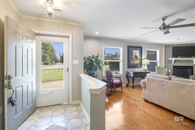 interior space featuring a brick fireplace, ornamental molding, and ceiling fan with notable chandelier