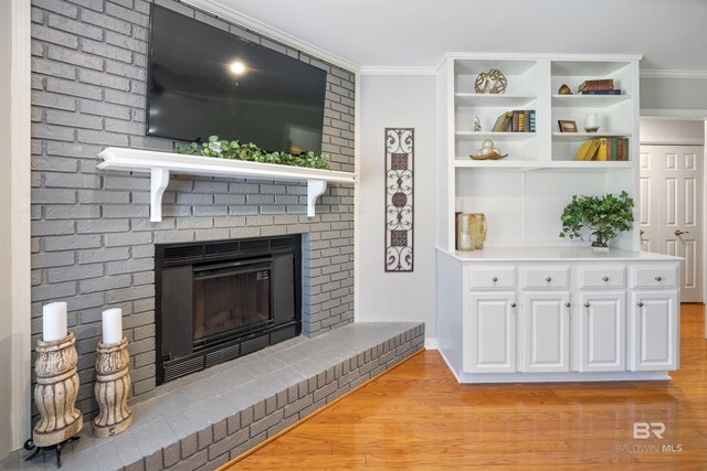 living room featuring light hardwood / wood-style flooring, a brick fireplace, and ornamental molding