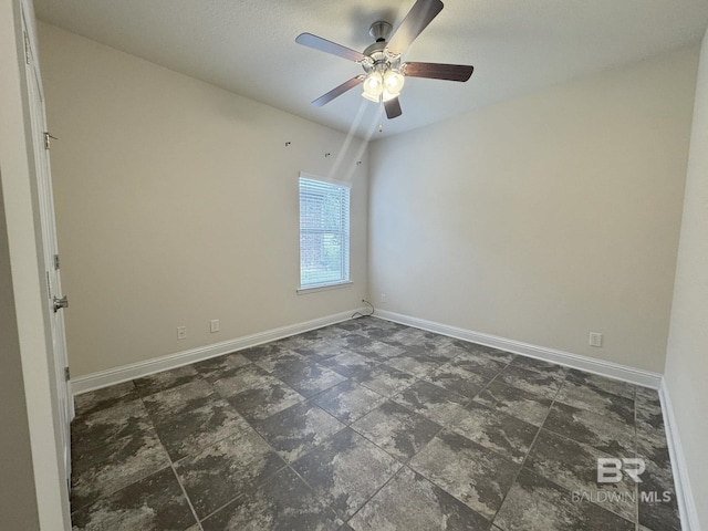 spare room with baseboards, a ceiling fan, and stone finish floor