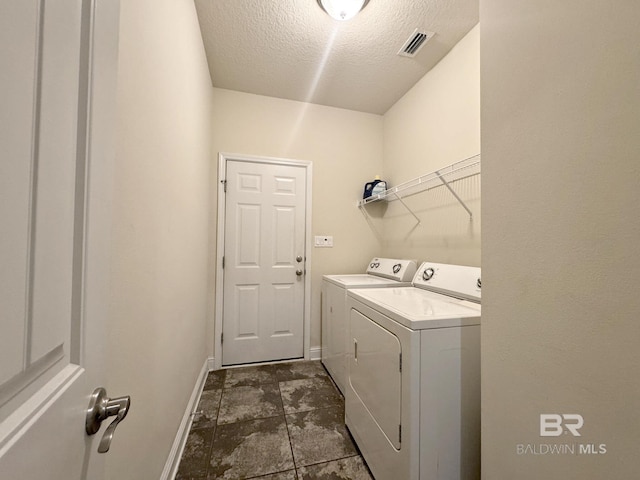 laundry area with washer and dryer, laundry area, a textured ceiling, baseboards, and visible vents
