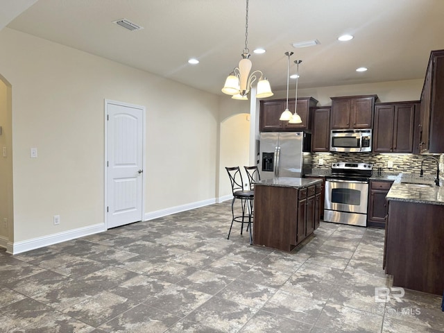 kitchen with arched walkways, baseboards, stainless steel appliances, and tasteful backsplash