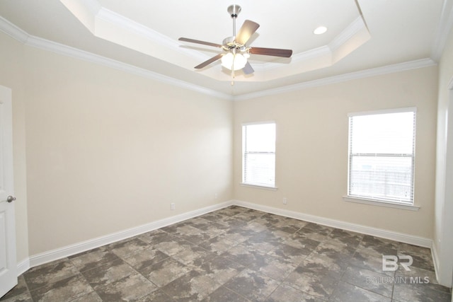 empty room featuring crown molding, baseboards, ceiling fan, a tray ceiling, and stone finish flooring