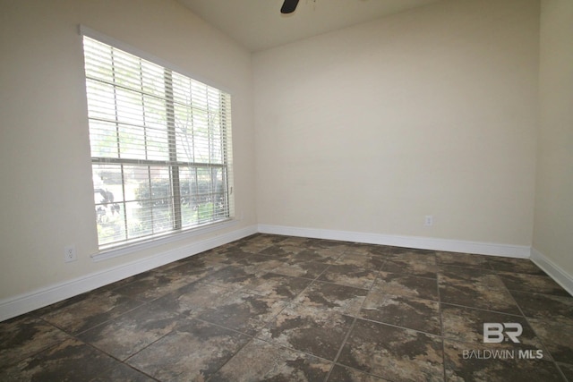empty room with stone finish floor, baseboards, and ceiling fan