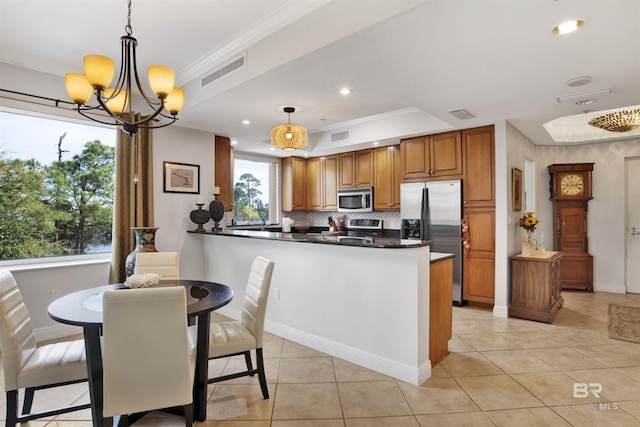 kitchen with stainless steel appliances, visible vents, decorative backsplash, brown cabinetry, and a peninsula