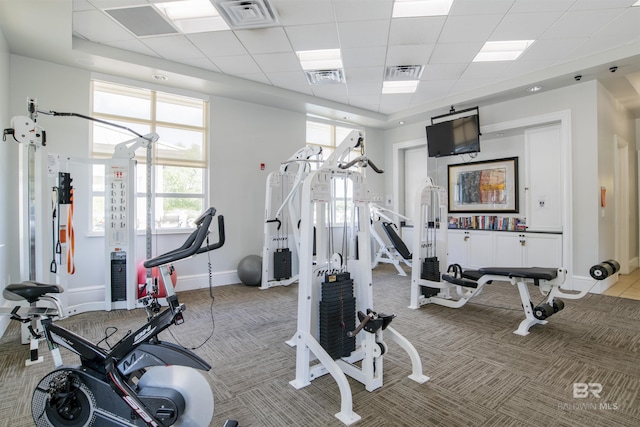 workout area featuring baseboards, visible vents, and light colored carpet