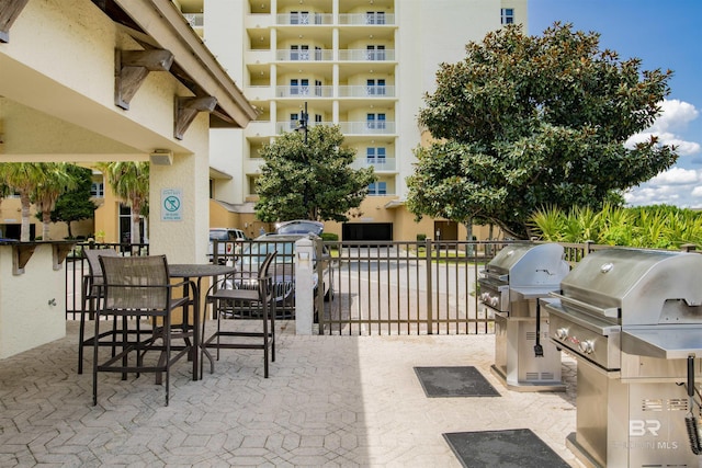 view of patio with outdoor dining area, area for grilling, fence, and an outdoor kitchen