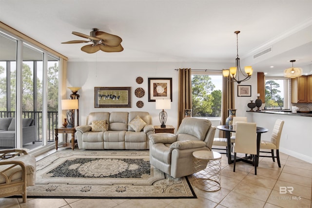 living area with ornamental molding, light tile patterned flooring, visible vents, and ceiling fan with notable chandelier