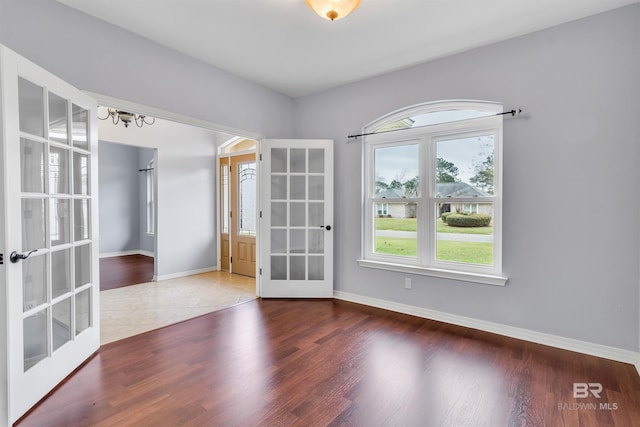 empty room with french doors, baseboards, and wood finished floors