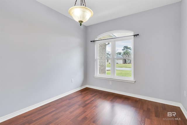 spare room with baseboards and dark wood-type flooring