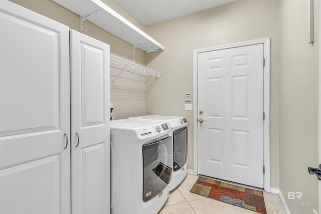 clothes washing area with laundry area, light tile patterned flooring, baseboards, and separate washer and dryer