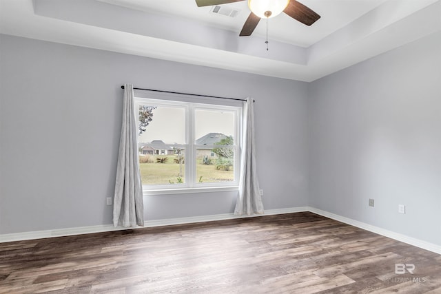 unfurnished room featuring baseboards, visible vents, a raised ceiling, and wood finished floors