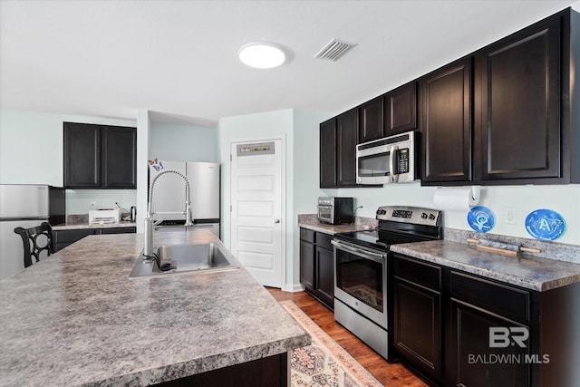 17372 Tallasee Blvd, Foley, AL 36535 - kitchen with appliances with stainless steel finishes, wood finished floors, and a center island with sink