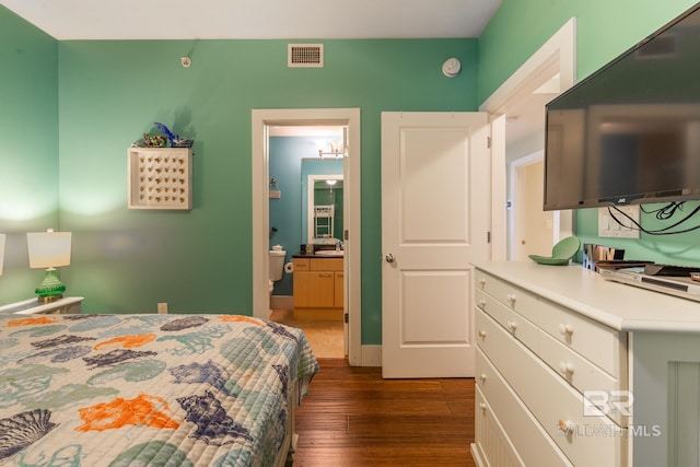 bedroom with connected bathroom and dark hardwood / wood-style floors