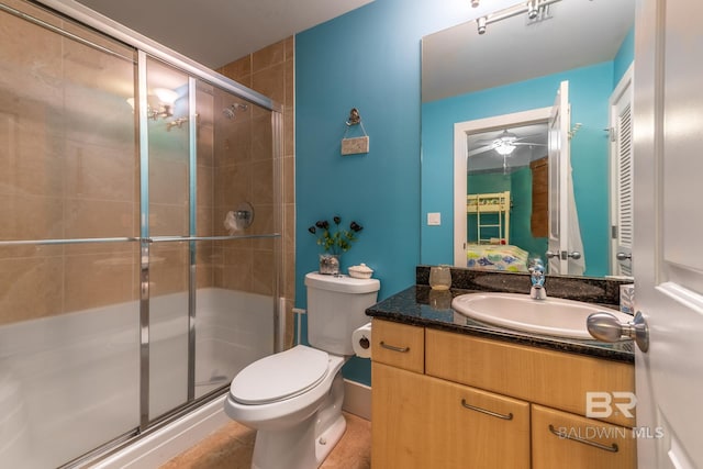 bathroom with vanity with extensive cabinet space, toilet, ceiling fan, tile flooring, and a shower with door