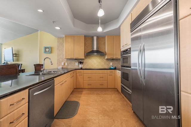 kitchen featuring stainless steel appliances, decorative light fixtures, a raised ceiling, light tile floors, and wall chimney range hood