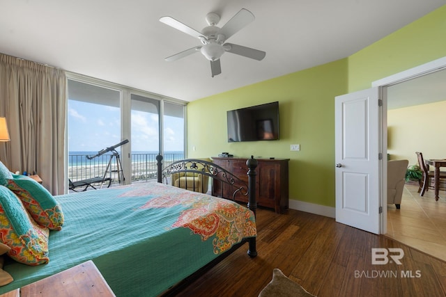 bedroom featuring ceiling fan, access to exterior, a water view, and dark wood-type flooring