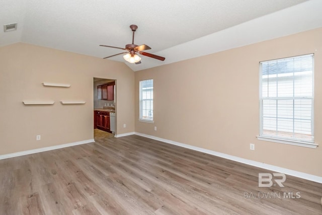 unfurnished room featuring ceiling fan, vaulted ceiling, light hardwood / wood-style flooring, and a textured ceiling