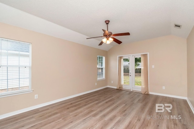 spare room with vaulted ceiling, ceiling fan, a textured ceiling, and light hardwood / wood-style floors