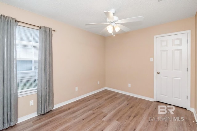 spare room featuring plenty of natural light, a textured ceiling, and light hardwood / wood-style flooring