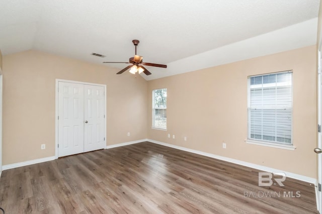 unfurnished bedroom with multiple windows, wood-type flooring, vaulted ceiling, and ceiling fan