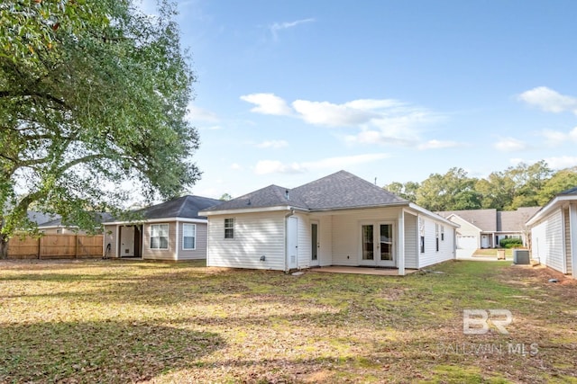 back of property with central AC and a lawn