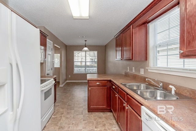 kitchen featuring white appliances, sink, hanging light fixtures, and a textured ceiling