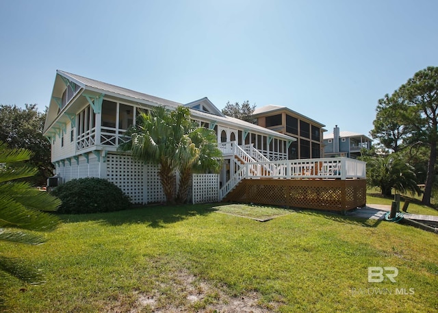 back of property featuring central air condition unit, a sunroom, a lawn, and a wooden deck