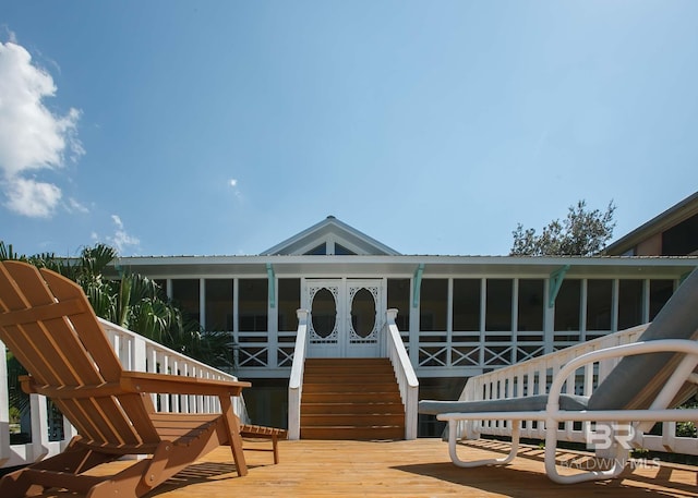 rear view of property featuring a sunroom and a deck