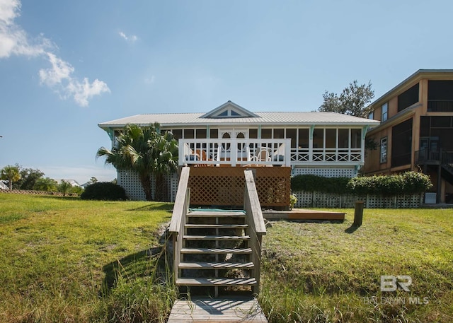 rear view of house featuring a yard, a sunroom, and a wooden deck