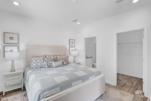 bedroom featuring ensuite bathroom, a closet, a walk in closet, and light hardwood / wood-style flooring