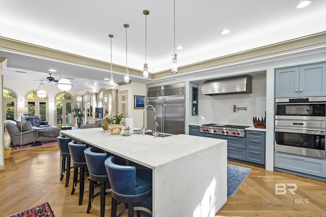 kitchen featuring appliances with stainless steel finishes, open floor plan, a breakfast bar area, wall chimney range hood, and recessed lighting