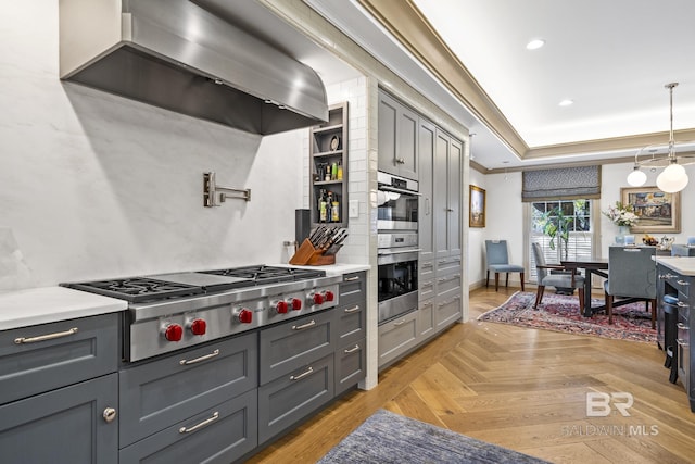 kitchen with appliances with stainless steel finishes, gray cabinets, and wall chimney range hood